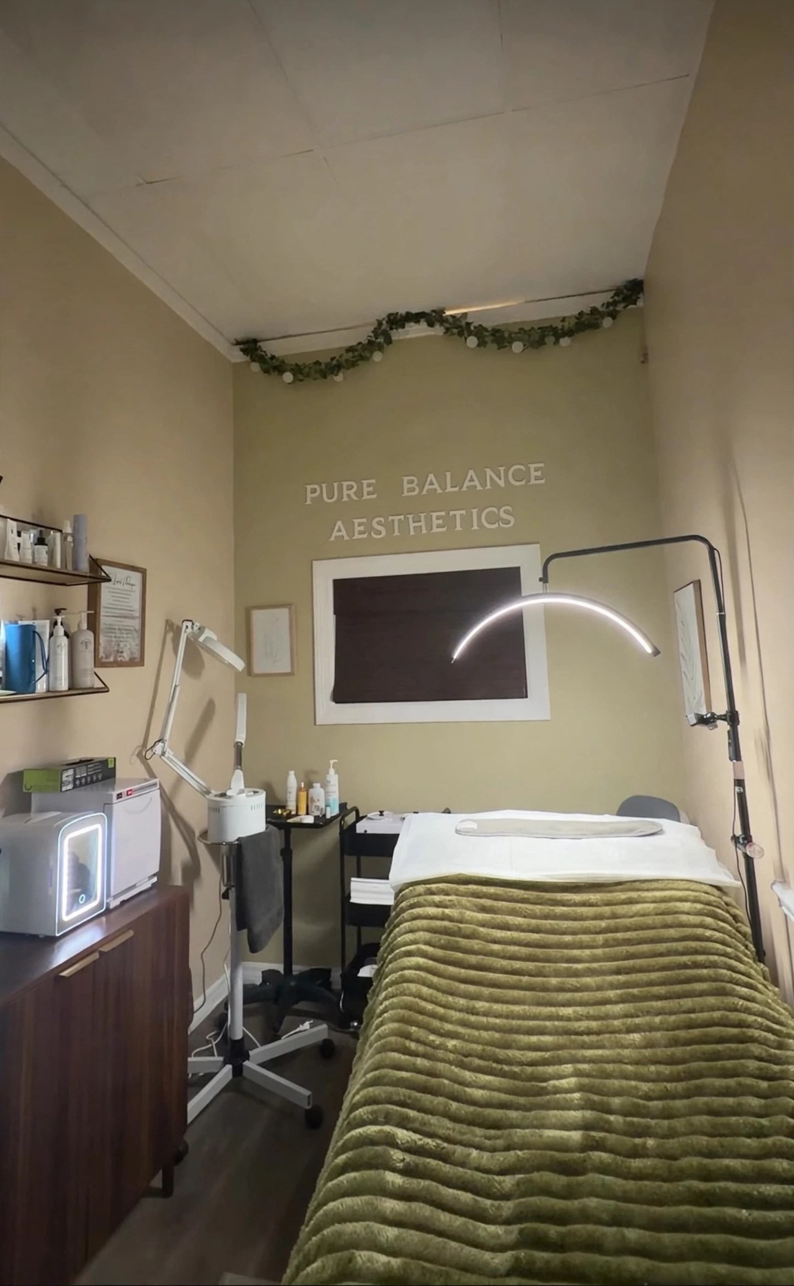 Inside the Skin Studio at D&H Hair Company — the treatment room with its treatment bed, arched lamp, and the Pure Balance Aesthetics sign on the wall