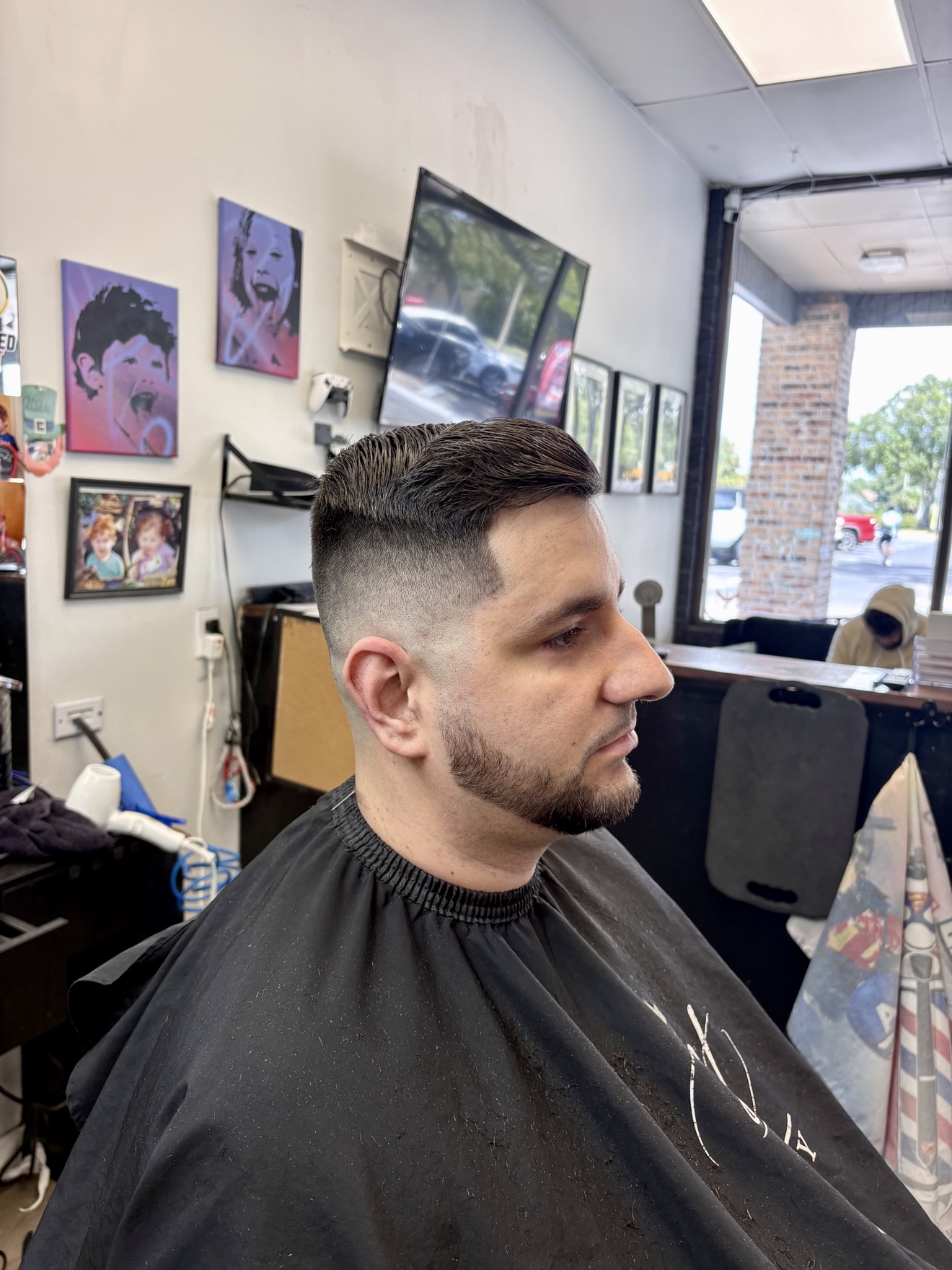 Skin fade with a slicked-back top and a sharp beard lineup, side view, by Danny at D&H Hair Company