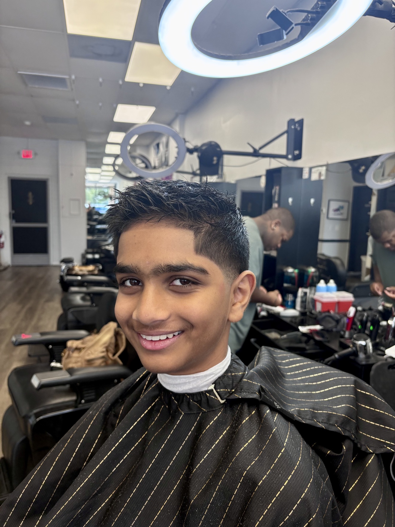Textured crop on a smiling young client in the barber chair, front view, by Danny at D&H Hair Company
