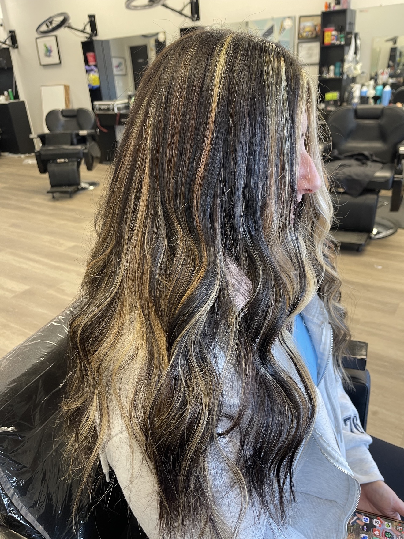 Long dark brown wavy hair extensions with blonde highlights, side view, by Heather at D&H Hair Company