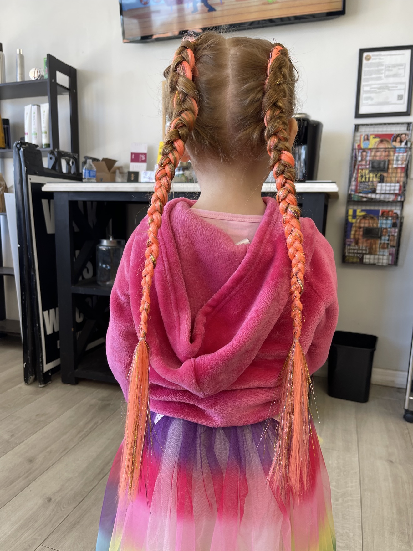 Double braids with coral color and tinsel on a young client, back view, by Heather at D&H Hair Company