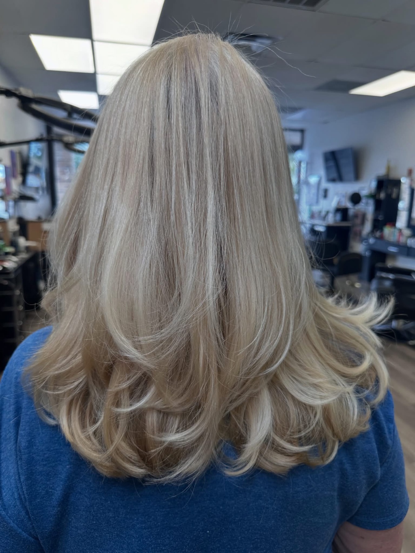 Blonde layered cut with a bouncy blowout, back view, by Lauren at D&H Hair Company