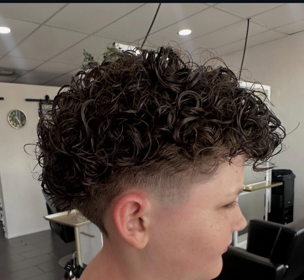 Dark curly perm with a tapered fade, side view, by Lauren at D&H Hair Company