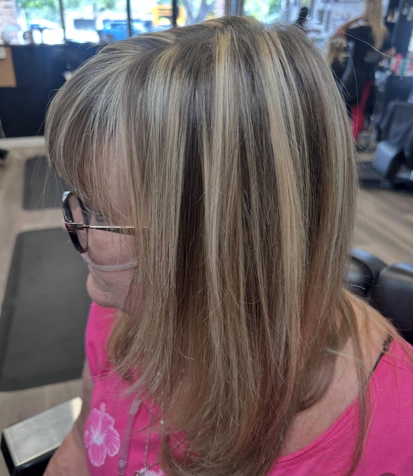 Long dimensional blonde hair with chunky highlights, side view, by Lauren at D&H Hair Company