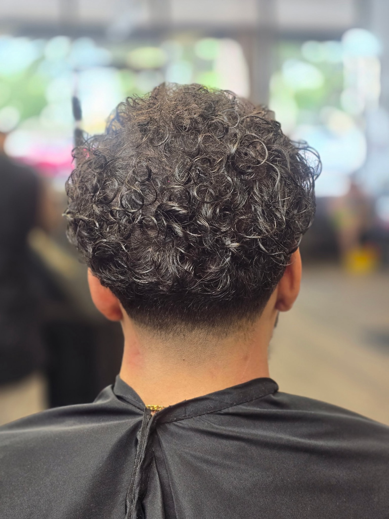 Curly cut with a taper fade, back view, by Rae at D&H Hair Company