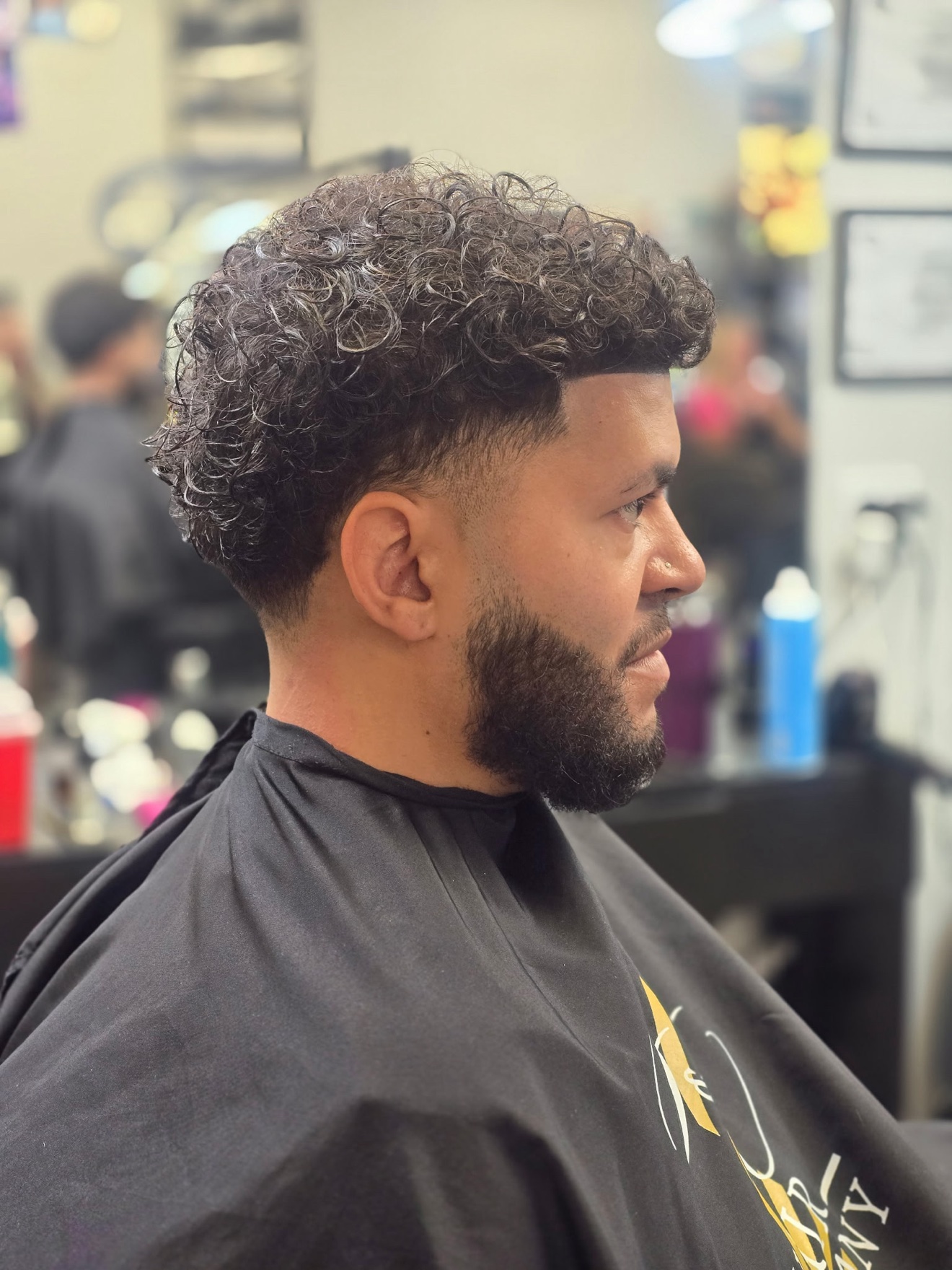 Curly cut with a taper and a shaped beard, side view, by Rae at D&H Hair Company